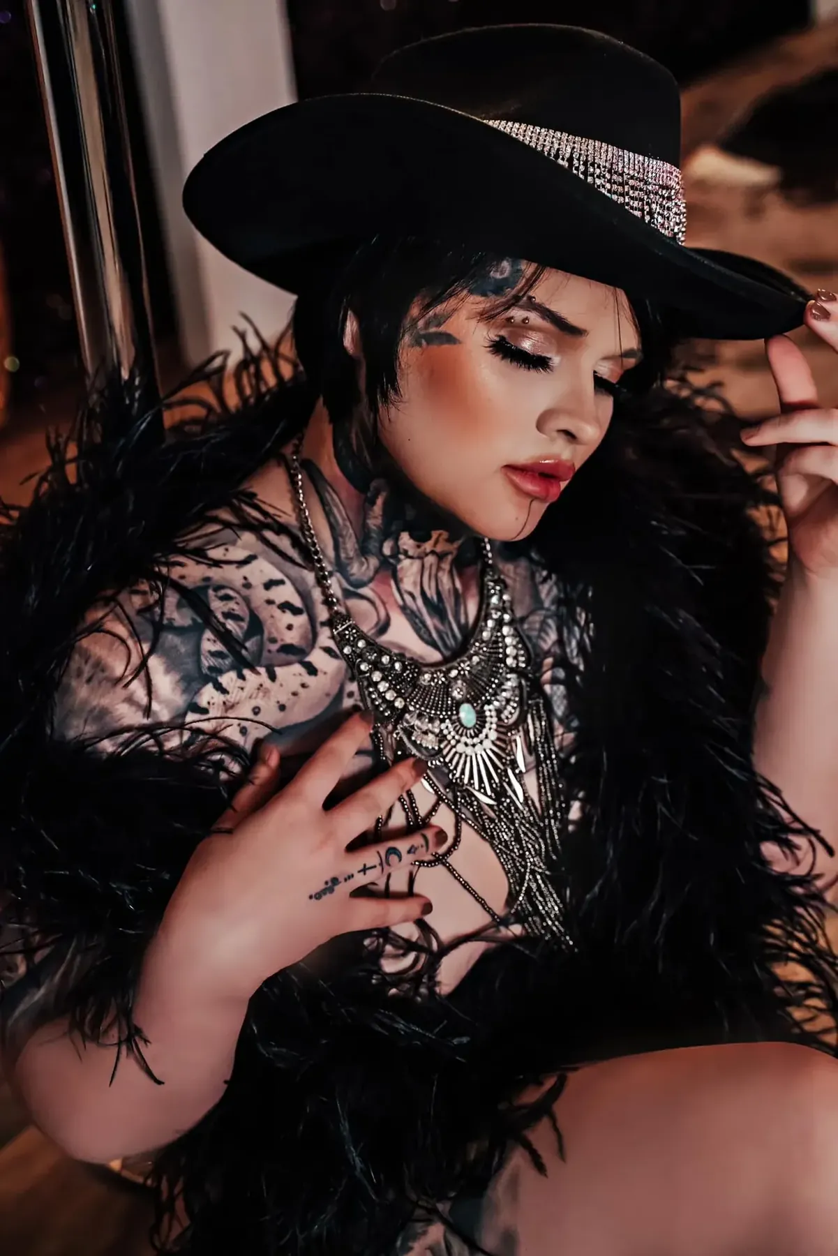 Client in a black wide-brim western hat, black feathers, and a statement silver necklace