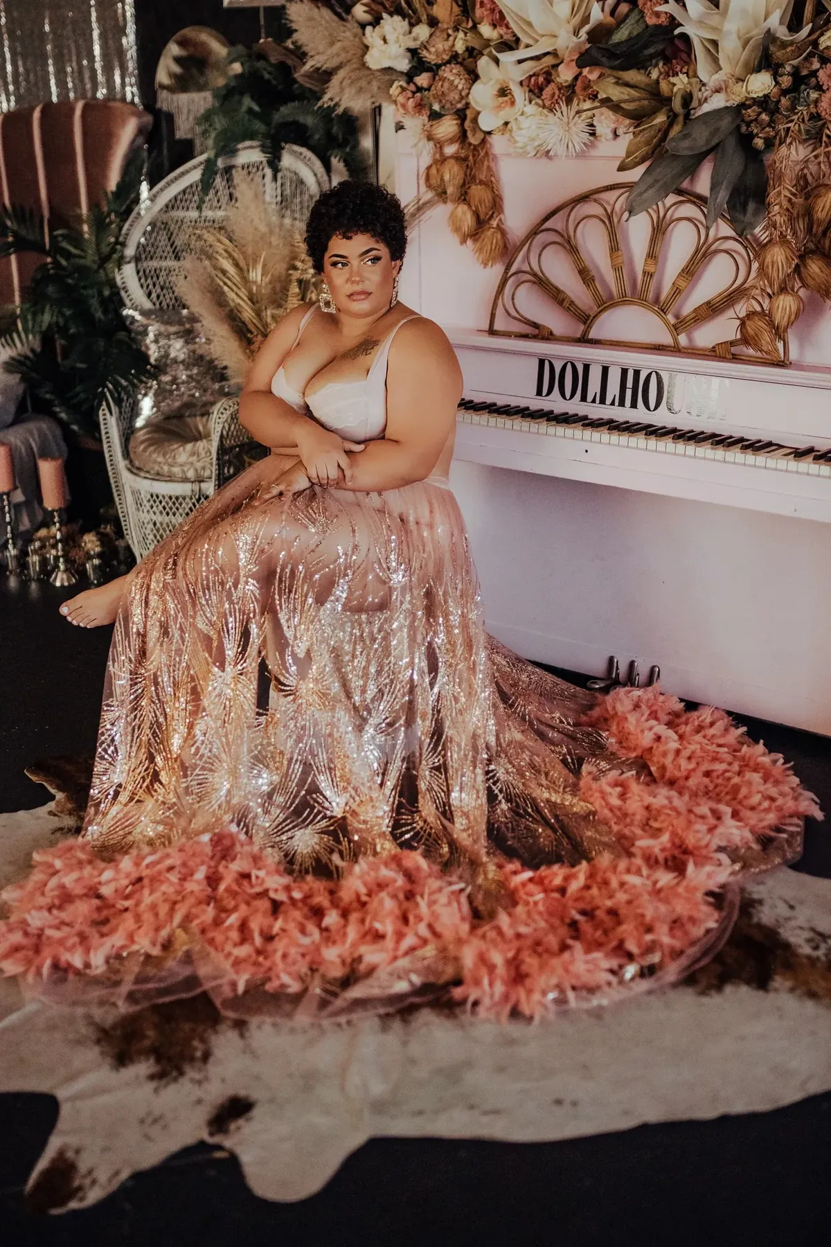 Client in a gold sequin gown seated beside the white studio piano